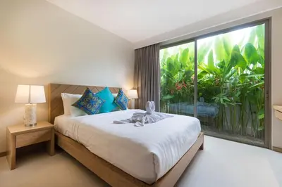 a bedroom with a bed with a large window at Trichada Tropical in Bang Tao Beach