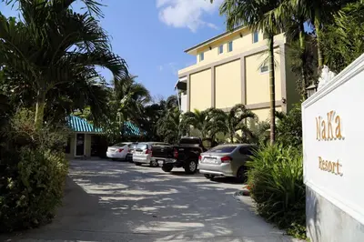 a street in front of a building with cars parked at Naka Resort in Kamala Beach