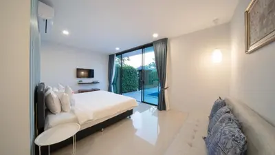 a bedroom with a bed and a couch and a window at Lespalm Taraburi Pool Villa SHA Plus in Thalang