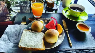 a plate of food with bread and fruit on a table at Le Passe-Temps in Tha Lane Bay