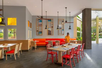 a restaurant with tables and chairs and a woman standing in the middle at Holiday Inn Resort Phuket, an IHG Hotel in Patong Beach