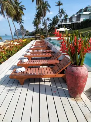 a row of wooden lounge chairs next to a pool at Saengsuree Villas Koh Yao Yai in Ko Yao Yai