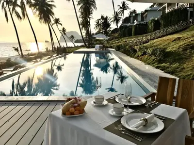 a table with a plate of food next to a swimming pool at Saengsuree Villas Koh Yao Yai in Ko Yao Yai