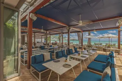 a restaurant with blue chairs and tables and the ocean at Twinpalms MontAzure Phuket in Kamala Beach