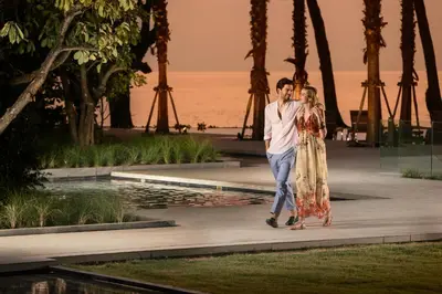 a man and a woman walking in front of the ocean at Twinpalms MontAzure Phuket in Kamala Beach