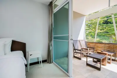 a bedroom with a glass door leading to a balcony at Kata Tranquil Villa - SHA Plus in Karon Beach