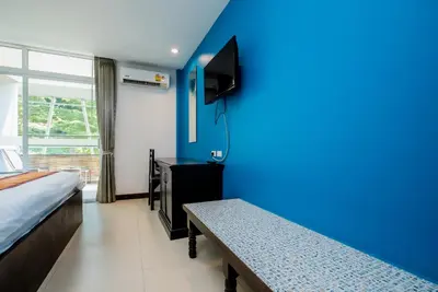 a room with a bed and a blue wall at Kata Tranquil Villa - SHA Plus in Karon Beach