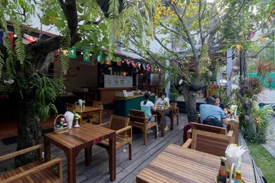 people sitting at tables in a restaurant with trees at Kata Tranquil Villa - SHA Plus in Karon Beach