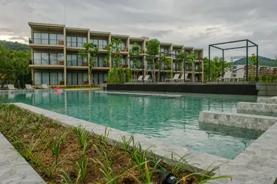 a building with a swimming pool in front of a building at The Gallery Hotel Nai Harn in Nai Harn Beach