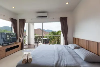 a bedroom with a bed and a television and a balcony at Number 4 Phuket in Nai Harn Beach