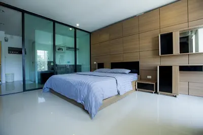 a bedroom with a large bed and glass walls at Number 4 Phuket in Nai Harn Beach
