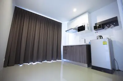 a kitchen with a refrigerator in front of a curtain at Number 4 Phuket in Nai Harn Beach