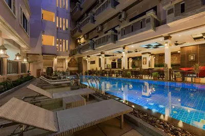 a large swimming pool in a building with tables and chairs at Seeka Boutique Resort in Patong Beach