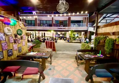 a restaurant with tables and chairs in a building at Sue@Cozy Guesthouse in Kata Beach