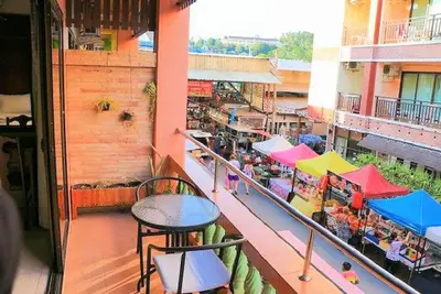 a balcony of a building with tables and umbrellas at Sue@Cozy Guesthouse in Kata Beach