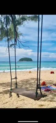a swing on a beach with the ocean in the background at Sue@Cozy Guesthouse in Kata Beach