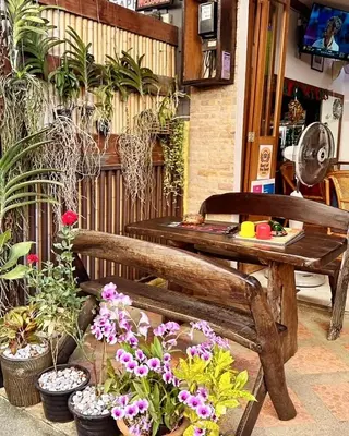 a wooden bench sitting next to a table and flowers at Sue@Cozy Guesthouse in Kata Beach