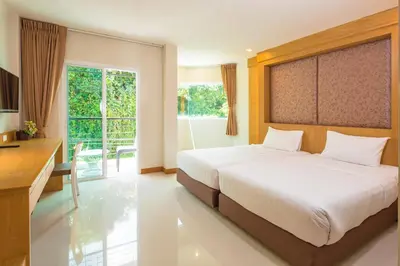 a bedroom with a bed and a desk and a window at Sungthong Kamala Beach Resort in Kamala Beach