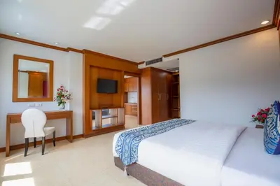 a bedroom with a bed and a desk and a television at Sungthong Kamala Beach Resort in Kamala Beach