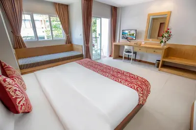 a bedroom with a bed and a desk and window at Sungthong Kamala Beach Resort in Kamala Beach