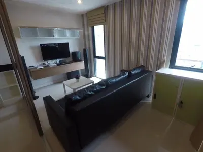 a living room with a black couch and a television at WOW Apartment at Unity Patong in Patong Beach