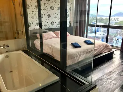 a bedroom with a bed and a tub and a mirror at WOW Apartment at Unity Patong in Patong Beach