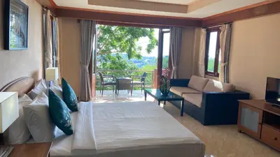 a bedroom with a bed and a living room with a balcony at Baan Kongdee Sunset Resort Kata in Kata Beach
