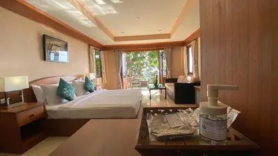 a hotel room with a bed and a table with a bottle of room moisturiser at Baan Kongdee Sunset Resort Kata in Kata Beach