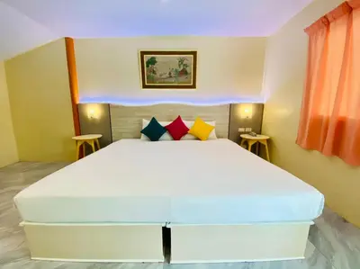 a bedroom with a large white bed with colorful pillows at Aochalong Villa Resort & Spa - SHA Plus in Chalong