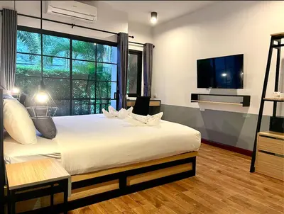 a bedroom with a large white bed and a flat screen tv at PP GRAND KAMALA HOTEL-SHA Extra Plus in Kamala Beach