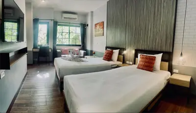 a hotel room with two beds and a table at PP GRAND KAMALA HOTEL-SHA Extra Plus in Kamala Beach