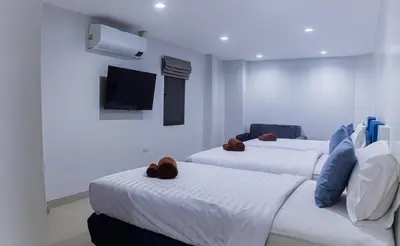 two beds in a room with a tv on the wall at Silla Patong Boutique - Beach Walk Access in Patong Beach