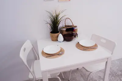 a white dining room table with two chairs and two plates at Baan Trok Bedroom Studio Maikhao in Mai Khao Beach
