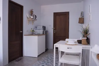 a kitchen with a white table and a white table and chairs at Baan Trok Bedroom Studio Maikhao in Mai Khao Beach