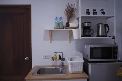 a kitchen with a sink and a microwave at Baan Trok Bedroom Studio Maikhao in Mai Khao Beach