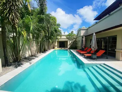 a swimming pool with chairs and umbrellas next to a house at Beautiful 3br 380sqm Pool Villa Walk To Bangtao Beach and Catch club in Bang Tao Beach