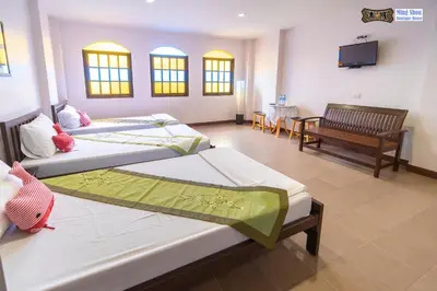 a room with three beds and a tv and a chair at Ming Shou Boutique House in Phuket Town