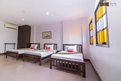 three beds lined up in a room with windows at Ming Shou Boutique House in Phuket Town