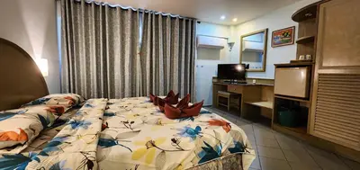 a bedroom with a bed and a desk and a television at Pension Zum Ross in Karon Beach
