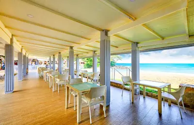 a restaurant with tables and chairs and the beach at Beyond Karon in Karon Beach