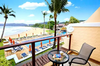 a balcony with a view of the beach and palm trees at Beyond Karon in Karon Beach
