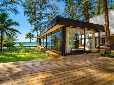 a house with glass walls and a wooden deck at Grand Villa Noi in Natai Beach