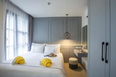 a bedroom with a white bed with yellow towels on it at Surin Beach Residence - Official Account in Surin Beach