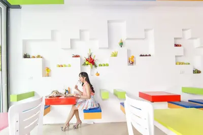 a woman sitting at a table in a room with colorful tables at The Frutta Boutique in Patong Beach