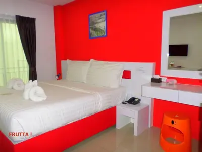 a red bedroom with a white bed and a red wall at The Frutta Boutique in Patong Beach
