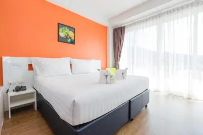 a large bed in a room with an orange wall at The Frutta Boutique in Patong Beach