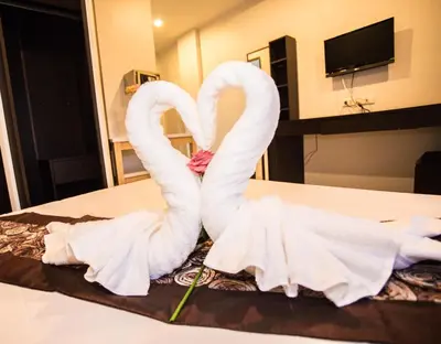 two swans made out of towels sitting on a bed at Happy 99 Guest house in Patong Beach
