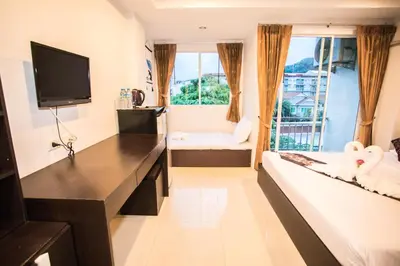 a hotel room with a bed and a television at Happy 99 Guest house in Patong Beach