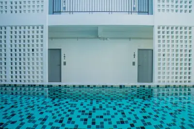 a swimming pool with blue tiled floors and doors at The Rubber Hotel Phuket in Thalang