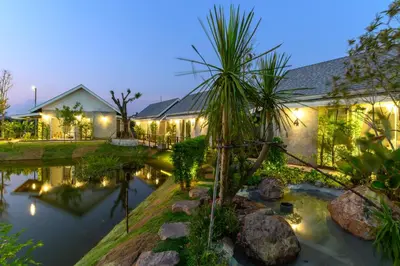 a house with a pond in front of it at Loftpical Resort in Phuket Town